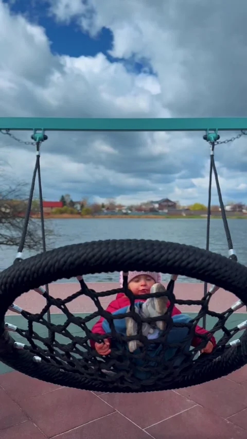 Kid Playing on Swing at Playground by Lake Видео 333149559