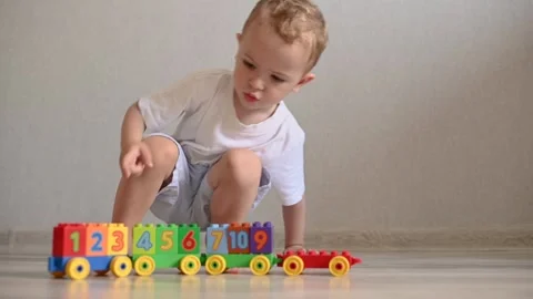 The kid is playing a train with trailers from the constructor with cubes with Stock-Footage 244923395