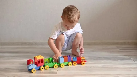 The kid is playing a train with trailers from the constructor with cubes with Stock-Footage 250199850