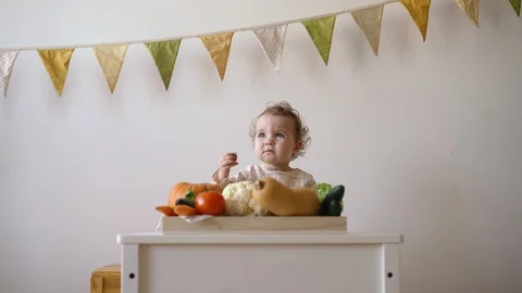 Kid playing with vegetables sitting at the table Stock Footage 128072668