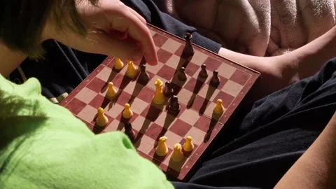 Kid plays chess alone with herself and explains the rules, how to move pieces. Vidéo 256376177