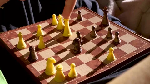 Kid plays chess alone with herself and explains the rules, how to move pieces. Vidéo 256376196