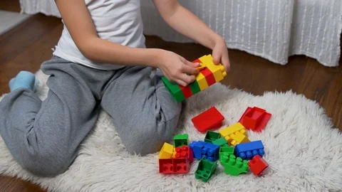 A kid plays with colored blocks. The child builds a house from blocks of the des Stock Footage 117620806