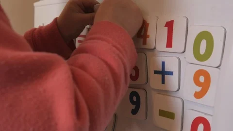 Kid plays with Magnets of simple Mathematical Numbers on a Refrigerator Stock Footage 87980824