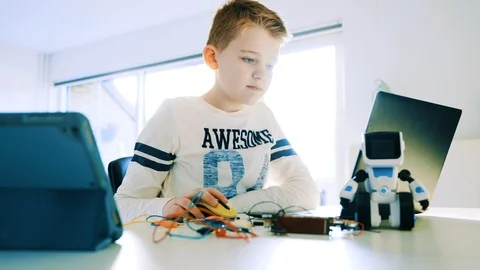Kid plays with a mini computer connected to his laptop computer Stock Footage 102173860