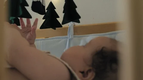 The kid plays with the mobile in the crib. Video stock 116473278