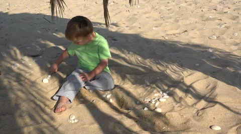 Kid plays with pebbles on sand Stock Footage 62815984