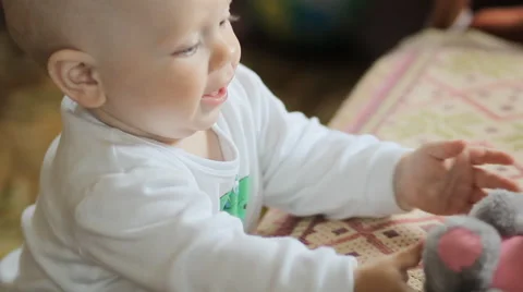 The kid plays with a teddy bear at home. Handsome boy less than a year Stock Footage 64557116