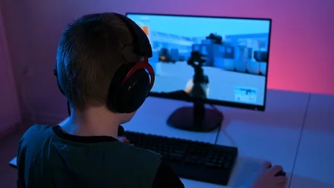 Kid plays video game on computer online while sitting at home at night Stock Footage 100725763