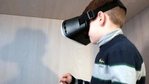 A kid plays virtual augmented reality game using head mounted display by usin Stock Footage 83881759