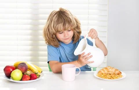 Kid pouring whole cows milk. Kid preteen boy 7, 8, 9 years old eating healthy Stock Photos