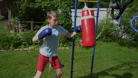 Kid practicing boxing skills at a home sports complex in the backyard Stock Footage 341360429