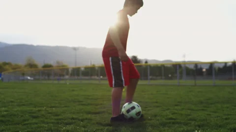 Kid practicing kicking soccer ball in park. Stock Footage 37408271