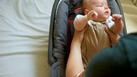 The kid is preparing to go for a walk. He is wearing seat belts in a carrying Stock Footage 92171398