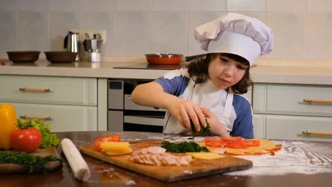 Kid preparing pizza. Boy sprinkles pizza with greens Stock Footage 125567817