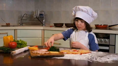 Kid preparing pizza. Child spread the filling on the dough for pizza Stock Footage 125566065