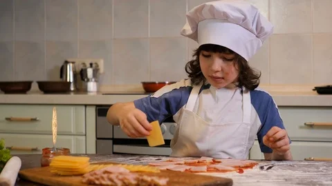 Kid preparing pizza. Child spread cheese on the dough for pizza Stock Footage 125566138