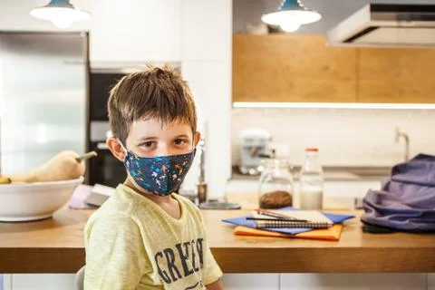 Kid with protective mask looking at camera at home. Stock Photos