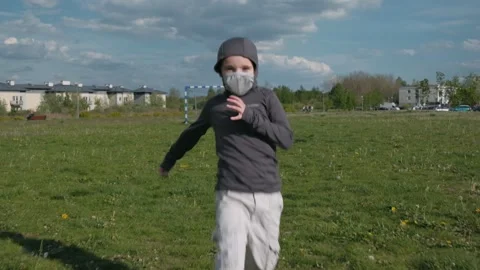 Kid with protective mask running on field. Active boy on nature. Slow motion Stock Footage 131097135