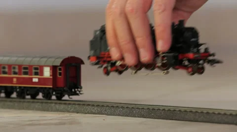 Kid puting toy train engine on track Video stock 37558375