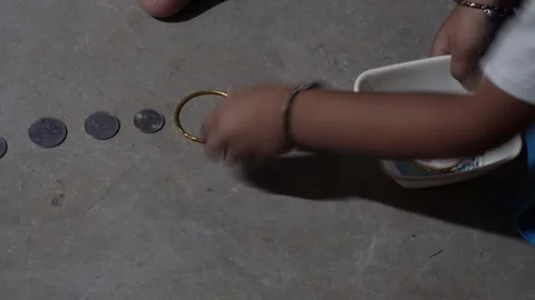 A kid is putting coins, bangles and other things into a white bowl Stock Footage 314563528