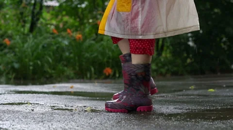 Kid in rain boots jumping chaotically in puddle Stock Footage 65270321
