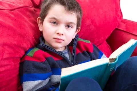Kid reading book on the couch Stock Photos