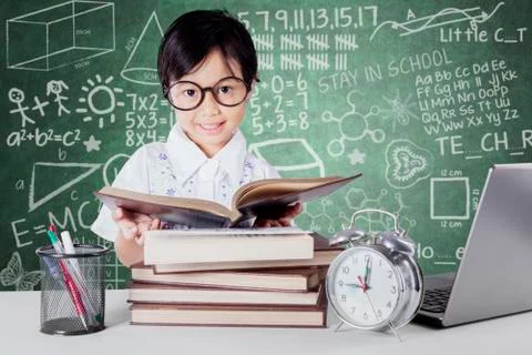 Kid reading books with clock on the table Stock Photos