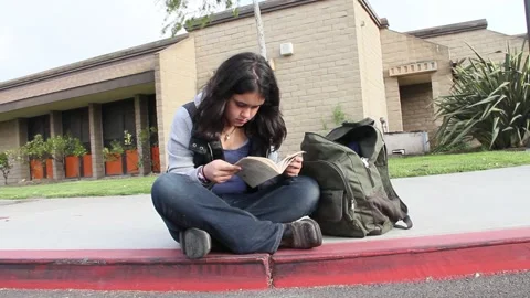 Kid reads book in front of school alone Stock Footage 155387881