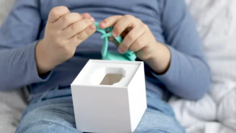 Kid receive smart watch in box as gift sitting on bed blanket Stock Footage 229295435