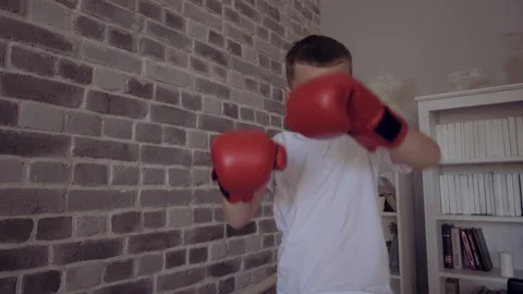 Kid in red boxing gloves training in his child room. Imagine to become the best Stock Footage 111547092