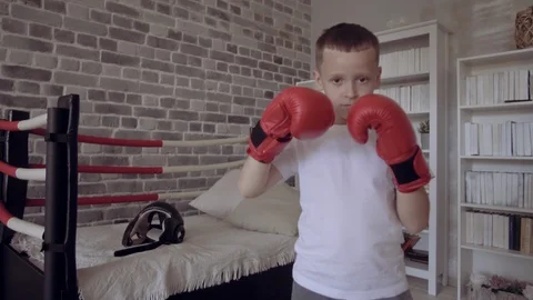 Kid in red boxing gloves training in his child room. Imagine to become the best Stock Footage 111552829