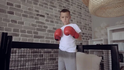 Kid in red boxing gloves training in his child room. Imagine to become the best Stock Footage 111556675