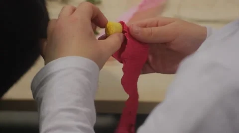 Kid is Rolling up a Red Paper Flower Making Paper Bouquet Sitting at the Table Stock Footage 61335045
