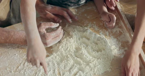 Kid' s hands playing with flour on wooden surface table in kitchen while Stock Footage 218629598