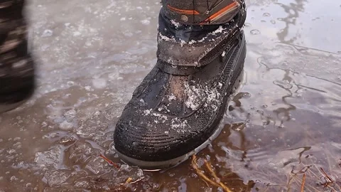 Kid 's Winter Boot Stepping on Melting Ice in a Winter Forest. kids Stock Footage 304586652