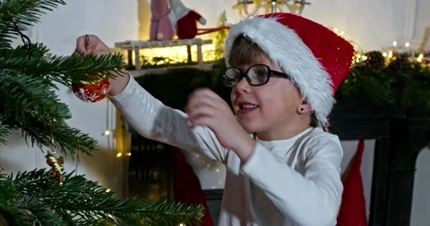Kid in Santa hat and red shirt point excitedly at an ornament Video stock 294693077