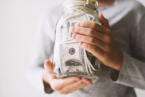 Kid save money. Put money in a piggy bank 库存照片