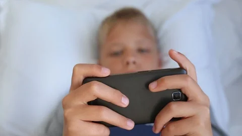 Kid of school age playing computer games using modern black smartphone Stock Footage 94770628