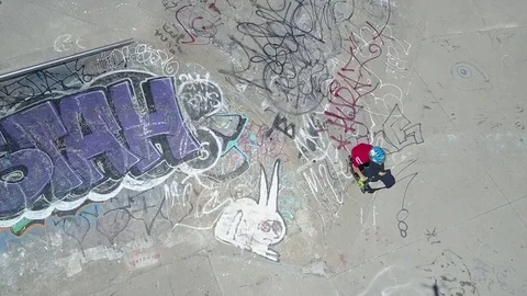 Kid on scooter rolling into skateboard park aerial view Stock Footage