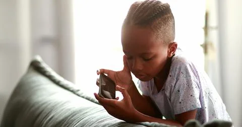 Kid scratching face while using phone playing game Stock Photos