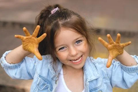 Kid with sequins on cheeks and on palms shows 10 fingers Stock Photos