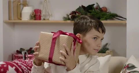 A kid shaking gift to find out what s inside Stock Footage 221812889