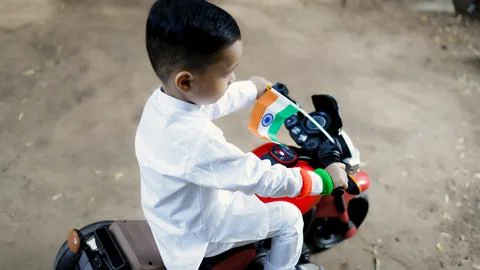 Kid showcasing national pride while wearing tricolor band and riding toy bi.. 스톡 사진