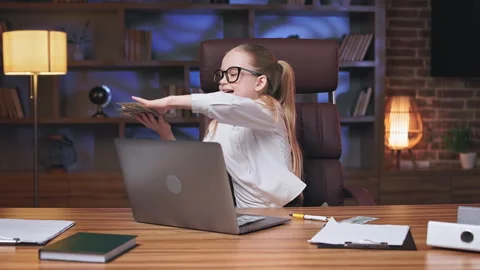 Kid showering cash while sitting at desk with laptop 動画素材 244648937