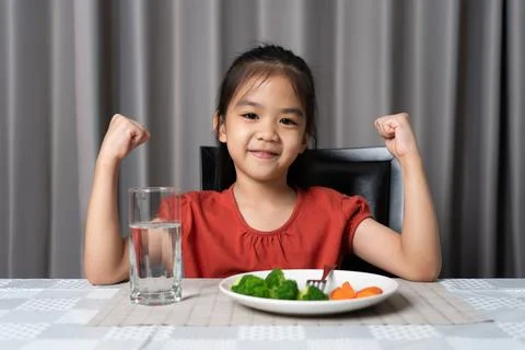 Kid shows strength of eats vegetables and nutritious food. Stock Photos