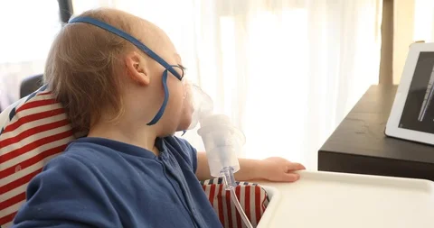 Kid sick in inhalation watching cartoon on tablet Stock Footage