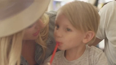 Kid sipping his soda, while his parents are looking at each other with a smile Stock Footage 77822560