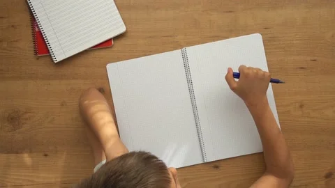Kid sit at table with open notebooks and tapping with pen. Education, learning Stock Footage 133498136
