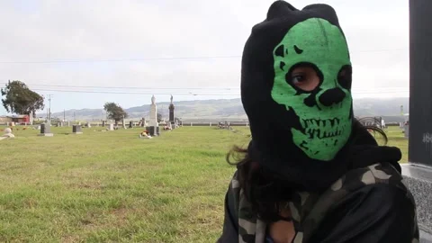 Kid sits in graveyard, wearing a skeleton mask Stock Footage 155327534